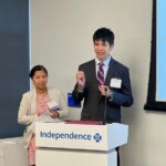 young adult standing at lectern with a woman standing nearby