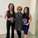 3 femails standing holding books